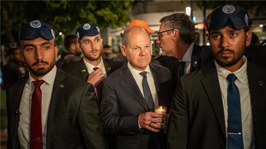 Bundeskanzler Olaf Scholz, umringt von Bodyguards, bei seinem Solidaritätsbesuch in Israel mit einer Kerze in der Hand am Dizengoff Square im Zentrum von Tel Aviv.