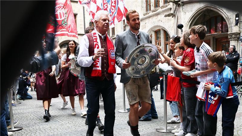 Bayern poltern und feiern - Dankbarer Müller sagt „Servus“ Bundesliga-Torschützenkönig Harry Kane trägt die Meisterschale flankiert von Oberbürgermeister Dieter Reiter (mit Fanschal) ins Münchner Rathaus.