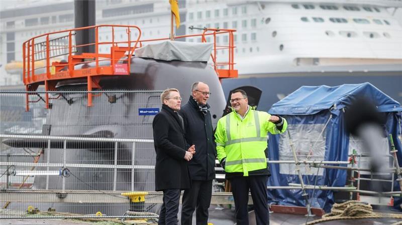 Burkhard erklärt Merz und Günther dabei die Arbeiten an einem U-Boot.