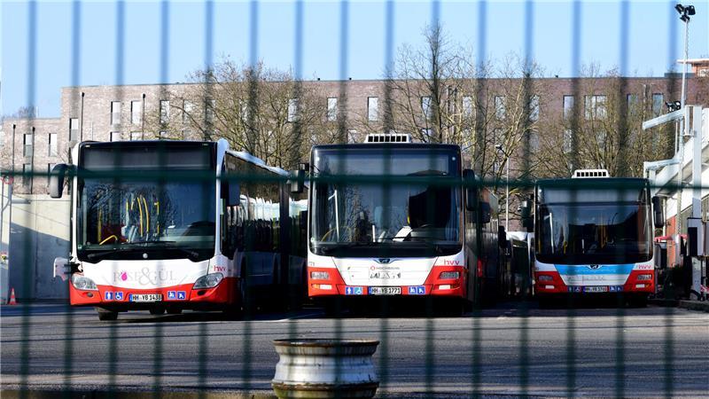 Busse der Hochbahn stehen auf einem Betriebshof hinter einem Zaun. 