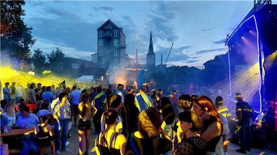 Feierlaunige stehen bei der Beach-Party am Buxtehuder Hafen im bunten Scheinwerferlicht 