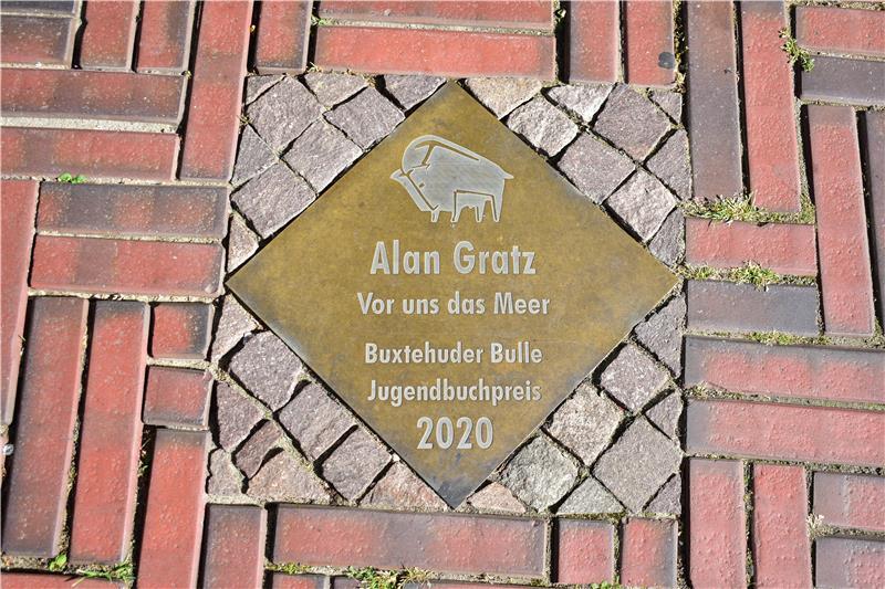Hollywoodreif: Mit ChatGPT auf Entdeckungsreise durch Buxtehude Messingplatte in einem Weg zu Ehren von Jugendbuchpreissieger Alan Gratz.