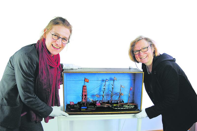Buxtehudes Museumsleiterin Dr. Susanne Keller (links) und die Kunsthistorikerin Susanne Mayerhofer präsentieren das pünktlich zum Gedenktag von Petra Kruse und Christiane Rosenkranz restaurierte Diorama mit dem Modell des Raddampfers „Primus“ (links). Fotos: Vasel/ Stadtarchiv