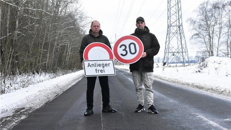Ralf Kimmel und Manuel Marquart stehen auf dem Hagener Weg und halten Verkehrsschilder in der Hand.
