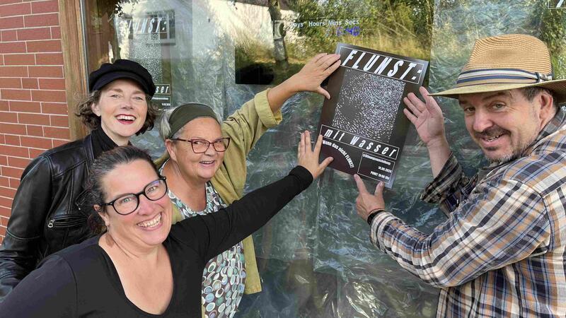 Carmen Breuker, Marlies Abramowski, Anja Tiedemann und Steffen Gill hängen das Flunst-Plakat am verhängten Ecks-Schaufenster auf (von links).
