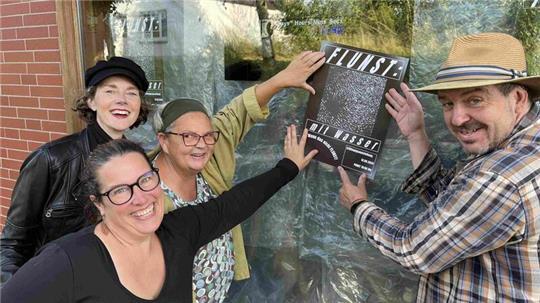 Carmen Breuker, Marlies Abramowski, Anja Tiedemann und Steffen Gill hängen das Flunst-Plakat am verhängten Ecks-Schaufenster auf (von links).