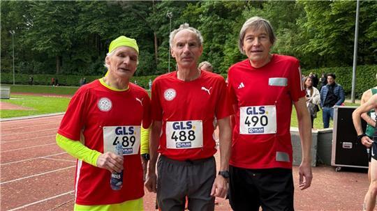 Carsten Kröger, Jörg Siebrands und Frank Kupper stehen mit Sportkleidung auf einer Tartanbahnund und schauen in die Kamera.