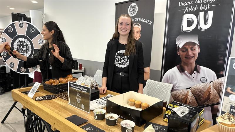 Celine Barg (rechts) erzählt Interessierten über die verschiedenen Ausbildungsberufe bei Schrader. Zudem locken ein Glücksrad und ein kleiner Stand mit Backwaren zahlreiche Besucher.