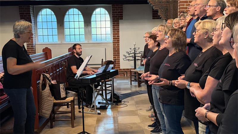 Chorleiterin Agnes Schrage (links), Pianist Fritz Krempien und die Happy Voices bei der Probe für das große Jubiläums-Konzert in der Apenser Kirche.