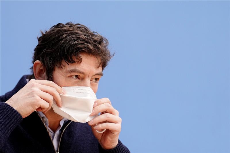 Christian Drosten, Direktor des Instituts für Virologie an der Charité Berlin, setzt sich seine FFP2-Maske in der Bundespressekonferenz zur aktuellen Corona-Lage auf. Foto: Kay Nietfeld/dpa