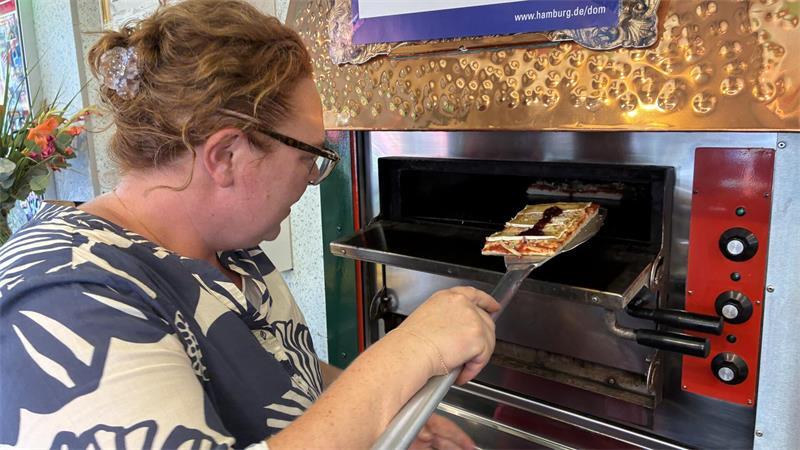 Mamamia! Mit Familie Greger abends auf dem Hamburger Sommerdom Christin Greger schiebt die Pizza in den Ofen, der je nach Andrang auf 250 bis 500 Grad Celsius geheizt wird.