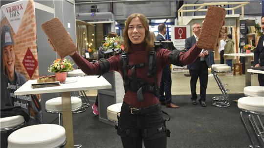 Christina Schött (Gesundheitsmanagement Viebrock) demonstriert ein Exoskelett, dass bei schweren Arbeiten den Rücken entlastet.