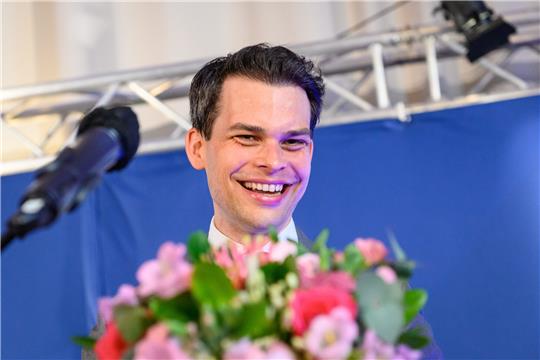 Christoph Ploß, Parteivorsitzender der CDU in Hamburg, lächelt hinter einem Blumenstrauß vor seiner Neuwahl zum Landesvorstand auf dem Landesparteitag der CDU Hamburg. Foto: Jonas Walzberg/dpa
