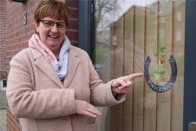 Claudia Bösch vom Schulförderverein Pfiffikus zeigt auf das Kinderinsel-Logo , das an der Scheibe des Horts in Himmelpforten gut zu sehen ist. Foto: Klempow