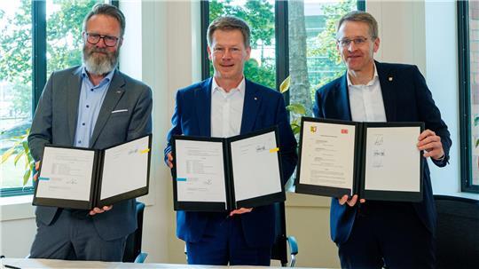 Claus Ruhe Madsen (CDU, l-r), Verkehrsminister, Richard Lutz, Vorstandsvorsitzender DB AG, und Daniel Günther (CDU), Ministerpräsident, zeigen eine unterzeichnete Kooperationsvereinbarung für die Planung zum weiteren Ausbau der Marschbahn. 
