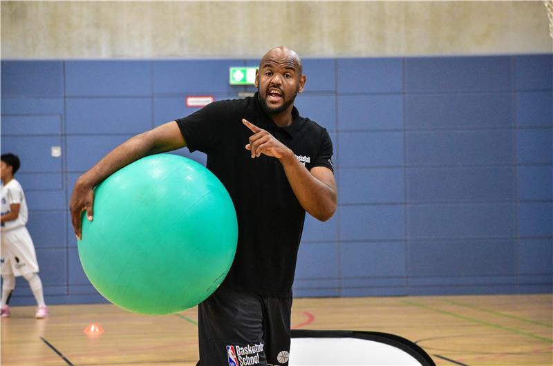 NBA-Camp in Stade: Junge Basketballer lernen von den Profis Paulo Prestes mit einem Gymnastikball gibt Anweisungen in der Sporthalle.