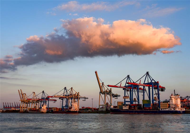 Containerschiffe werden im Hafen im Licht der untergehenden Sonne abgefertigt. Foto: Axel Heimken/dpa