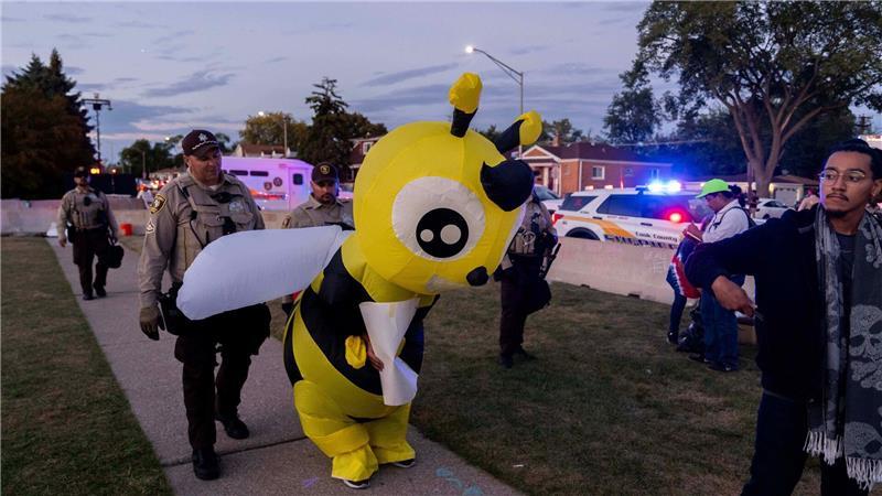 Cook County Sheriffs ziehen einen Demonstranten in einem Kostüm zurück, während sie eine Ausgangssperre vor der US-Einwanderungs- und Zollbehörde in Broadview, Illinois, durchsetzen.