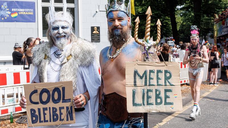 „Cool bleiben“ und „Meer Liebe“ steht auf einem der Schilder der verkleideten Teilnehmenden.