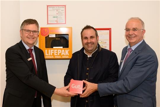 Cord Köster (Sparkasse Harburg-Buxtehude), Jan Bauer (DRK) und Wilfried Wiegel (Sparkasse) vor dem neuen Defibrillator im Beratungscenter Buchholz der Sparkasse Harburg-Buxtehude.