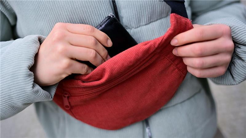Ripp-Chic für „Drinnies“? Warum es ein Cord-Comeback gibt Cord lässt sich im Alltag wieder öfter antreffen; Eine Frau trägt eine Jacke und eine Brusttasche aus Cord und steckt ihr Portemonnaie in die Tasche. (Foto: Illustration)