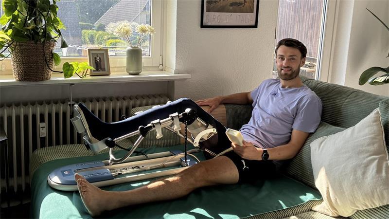 D/A-Innenverteidiger Tjorve Mohr hat sein Bein in einem Gerät eingespannt, das die Streckung und die Beugung des Kniegelenks unterstützt.