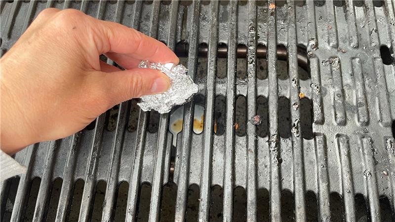 DIY-Trick: Ein zur Kugel gedrücktes Stück Alufolie soll angebrannte Reste vom Grillrost entfernen. 