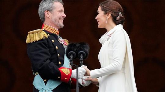 Dänemarks König Frederik X. und Dänemarks Königin Mary halten sich auf dem Balkon von Schloss Christiansborg die Hände.