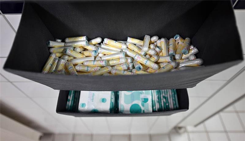 Damenbinden und Tampons liegen auf einem Damen-WC aus. Foto: Martin Schutt/dpa