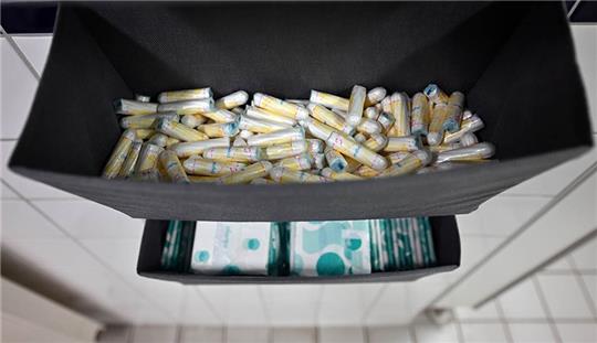 Damenbinden und Tampons liegen auf einem Damen-WC aus. Foto: Martin Schutt/dpa