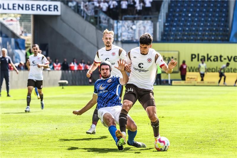 Damian Roßbach (Mitte) von Hansa Rostock und Igor Matanovic von St. Pauli in Aktion. Foto: Sebastian Heger/dpa