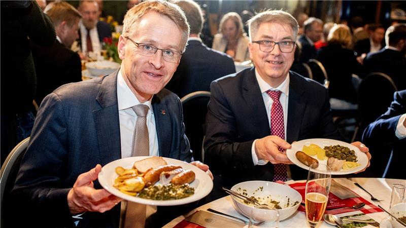 Daniel Günther (l), der Ministerpräsident von Schleswig-Holstein, ist der neue Oldenburger Grünkohlkönig. Hier beim Essen mit dem Oldenburger Oberbürgermeister Jürgen Krogmann (SPD). Auf den Tellern haben sie eine Portion Grünkohl und den klassischen Beilagen Kartoffeln, Pinkel, Kochwurst und Kassler.