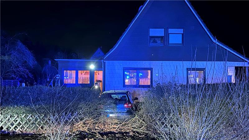 Das Auto durchbricht Zaun und Hecke und landet im Vorgarten eines Einfamilienhauses.