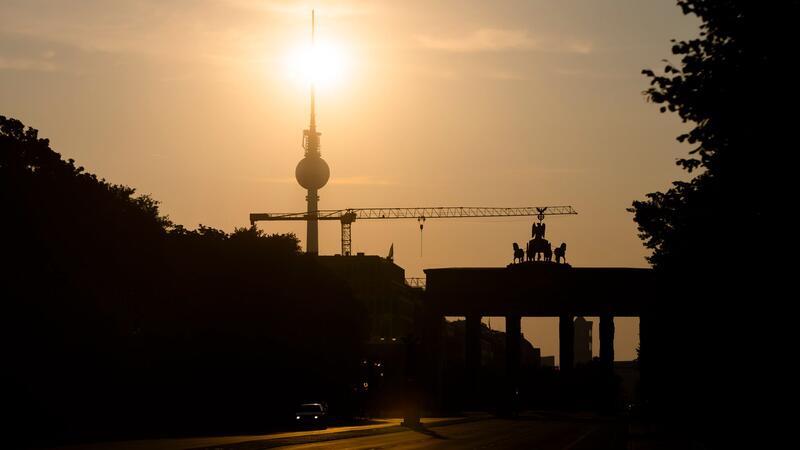 Wetterdienst erwartet Sommer-Intermezzo Das Brandenburger Tor und der Fernsehturm sind im Gegenlicht der aufgehenden Sonne zu sehen. Am Montag zeigt sich laut Vorhersage meist die Sonne, höchstens wird es locker bewölkt.