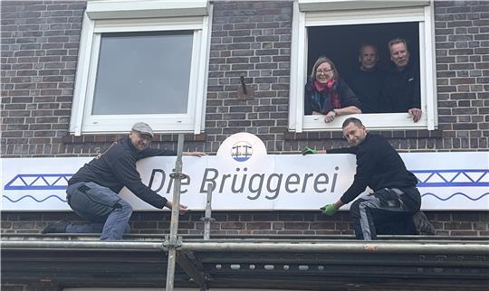 Das Brüggerei-Schild wird von Dr. Jan Sulzer und Bo Willem Friedrichsen in Estebrügge montiert.