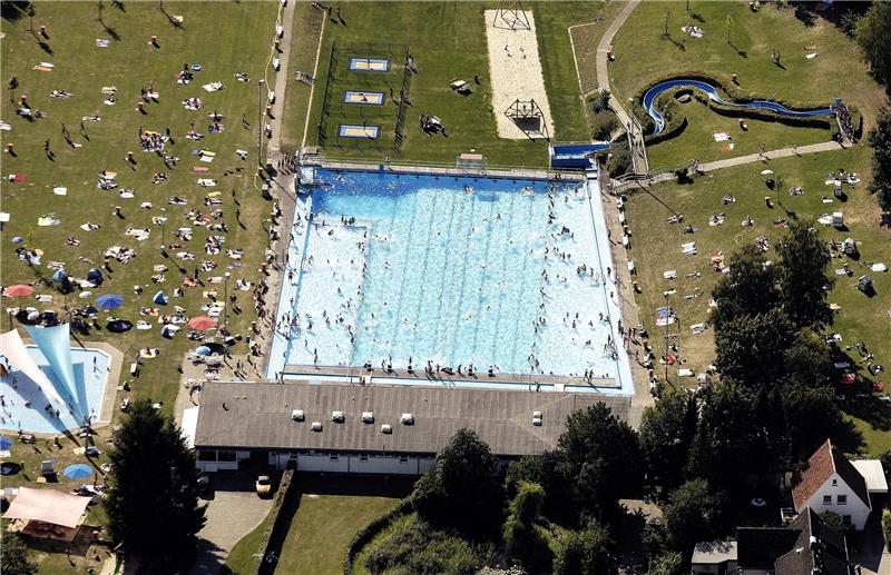 Das Buxtehuder Freibad von oben: Die helleren Flächen rechts und links sind die Nichtschwimmerbereiche, dazwischen sind acht Schwimmerbahnen sowie die nicht voll nutzbare Schwimmerbahn außen rechts erkennbar, zu der ein Stück Treppe gehört 