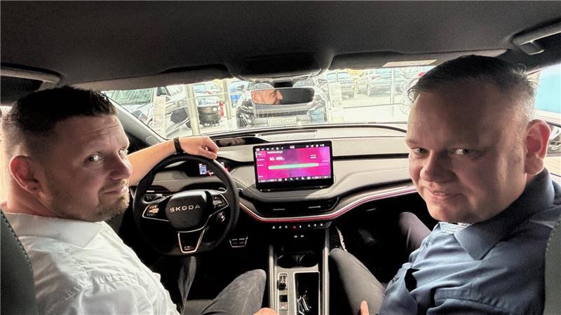 Das Display im E-Auto-Cockpit zeigt den Batterieladestand - oder auf Wunsch auch Kinderfilme: Verkaufsleiter Niko Spittkau (links) sowie Autohausinhaber und Kfz-Innungsobermeister Ulrich Tietjen sitzen in einem Skoda Enyaq.