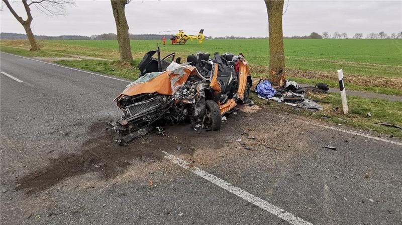 Das Fahrzeugwrack nach dem Unfall: Im Hintergrund ist der Rettungshubschrauber zu sehen, der auf einem Feld landete. Foto: Polizei