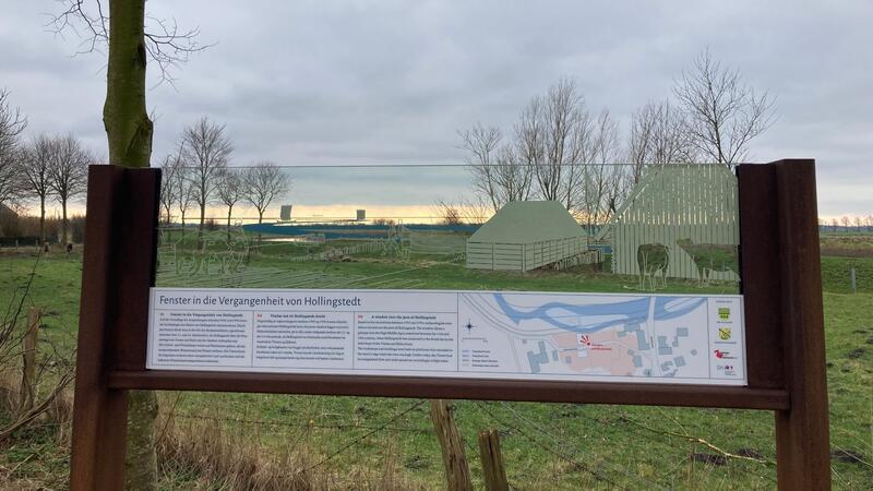 „Fenster in die Vergangenheit“ zeigt Hafen von Haithabu Das „Fenster in die Vergangenheit“ steht vor einer Wiese an der Treene.
