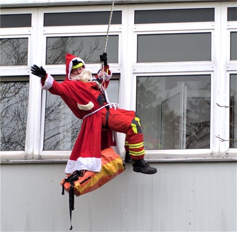 Das Feuerwehr-Rot passt gut zur Uniform des Nikolauses: Rene Haase seilt sich zur Freude der Kinder vom Klinik-Dach ab. Foto: Hußendörfer