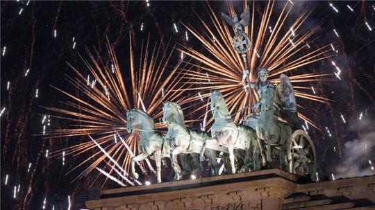 Das Feuerwerk zum Jahreswechsel steigt hinter dem Brandenburger Tor auf.