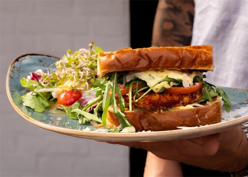 Das Gericht „Brioche Crispy Chicken“: Das Il Mulino serviert ein Sandwich mit Huhn, Tomate, Rucola und Parmesan sowie einem Salat.