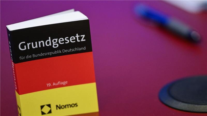 Was bedeutet das Gutachten zur AfD in Brandenburg? Das Grundgesetz in Miniatur-Ausgabe steht bei der Pressekonferenz zur AfD auf einem Tisch.