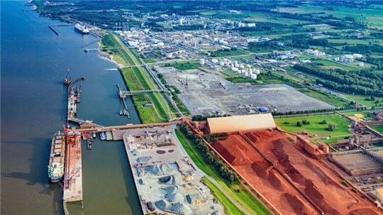 Das Industriegebiet Bützflethersand mit dem Hafen (links unten), der AOS und ihrem roten Gestein, der Baufläche fürs LNG-Terminal in der Mitte sowie dahinter und daneben die großen Flächen der Dow mit dem Gasanleger (hinten links).