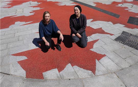 Das Künstlerinnenduo "missing icons", Andrea Knobloch (r) und Ute Vorkoeper, sind auf der großflächigen Bodenskulptur "Stigma" vor der ehemaligen Gestapo-Zentrale an der Stadthausbrücke zu sehen. Foto: Marcus Brandt/dpa