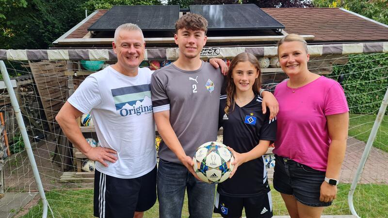 Die Familie Brugner steht im Garten vor einem Fußballtor.