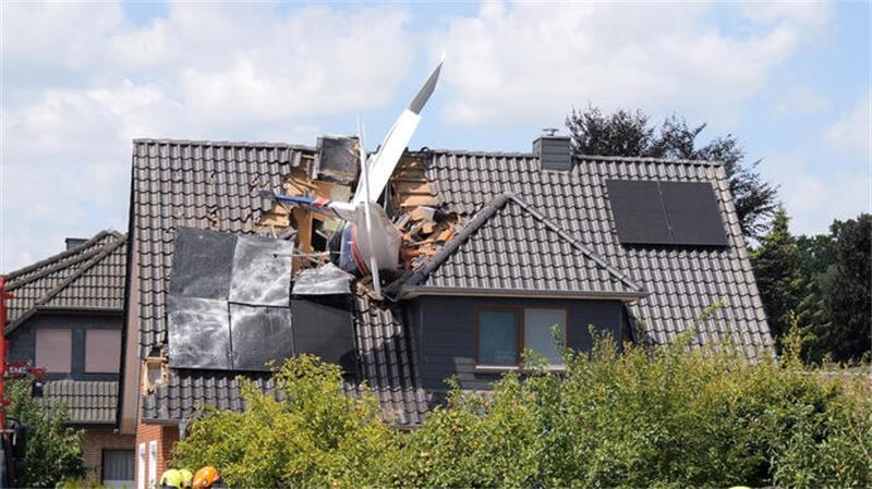 Das Leichtflugzeug steckt im Dach eines Hauses.