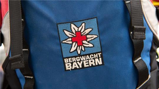 Das Logo der Bergwacht ist an einem Rucksack zu sehen. Bei Oberstdorf musste die Bergwacht nun einen Mann retten, der ohne richtige Ausrüstung und Erfahrung zwei Nächte in den Bergen verbrachte. (Archivfoto-Illustration)