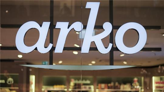 Das Logo der Firma arko leuchtet in Hamburg am Eingang einer Filiale.