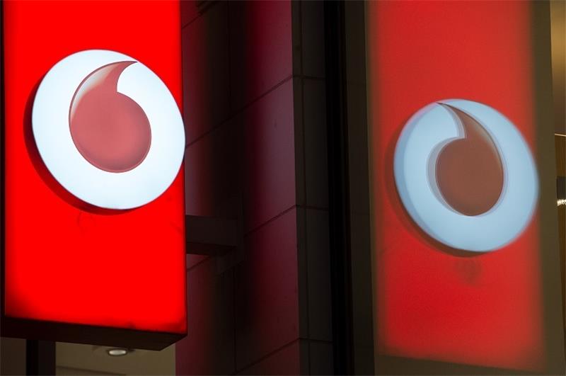 Das Logo von Vodafone spiegelt sich in der Fensterscheibe einer Verkaufsfiliale des Unternehmens. Foto: Rainer Jensen/dpa
